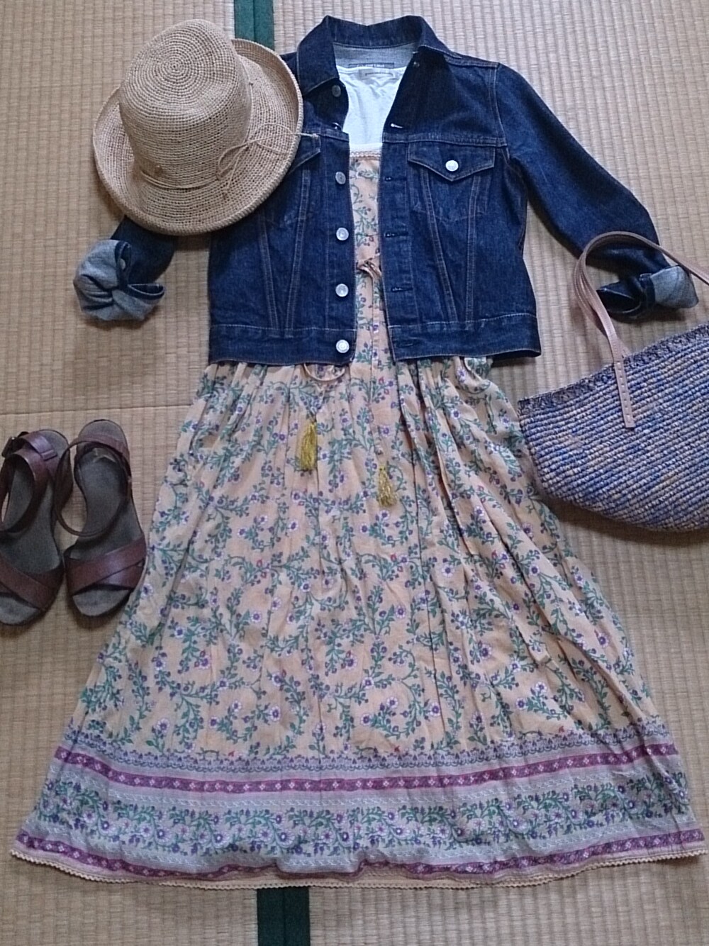 オレンジ系のワンピース、ブラウン系のサンダル、ブルー系のデニムジャケットを着用したレディースの春コーディネートの1枚目の写真