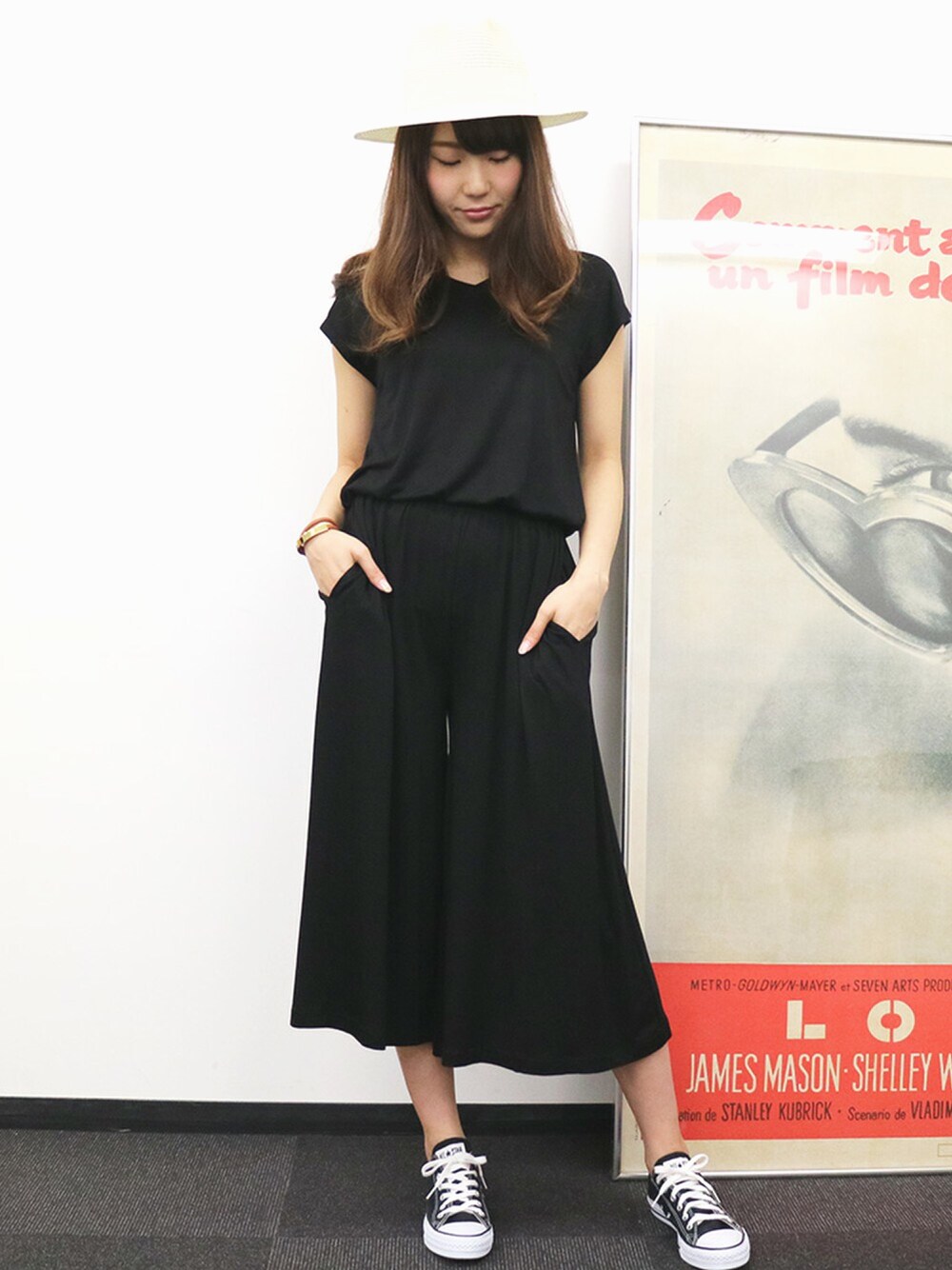 ブラック系のつなぎ/オールインワン、ブラック系のスニーカー、ホワイト系のハットを着用したレディースの春コーディネートの1枚目の写真