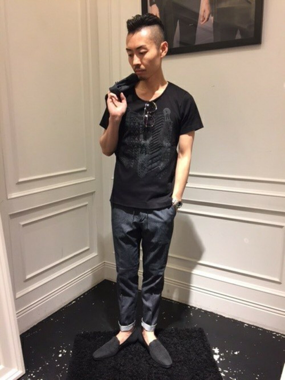 ブラック系のTシャツ/カットソー、ブラック系のスリッポン、ブルー系のデニムパンツを着用したメンズの夏コーディネートの1枚目の写真