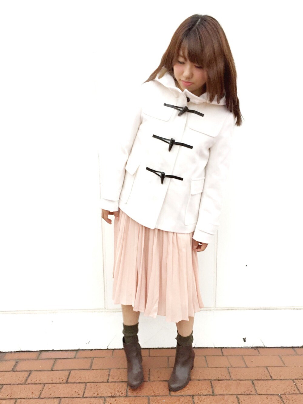 ピンク系のスカート、ホワイト系のダッフルコート、ブラウン系のブーツを着用したレディースの秋コーディネートの1枚目の写真