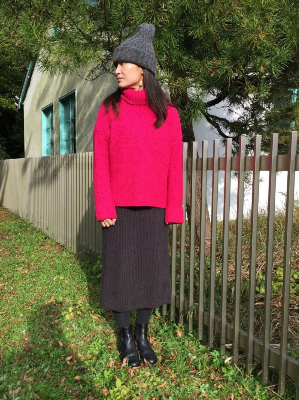 レッド系のニット/セーター、グレー系のワンピース、ブラック系のブーツを着用したレディースの秋コーディネートの1枚目の写真