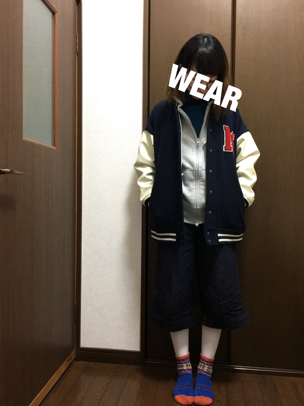 ブルー系のニット/セーター、グレー系のパーカー、ブルー系のスタジャンを着用したレディースの冬コーディネートの1枚目の写真