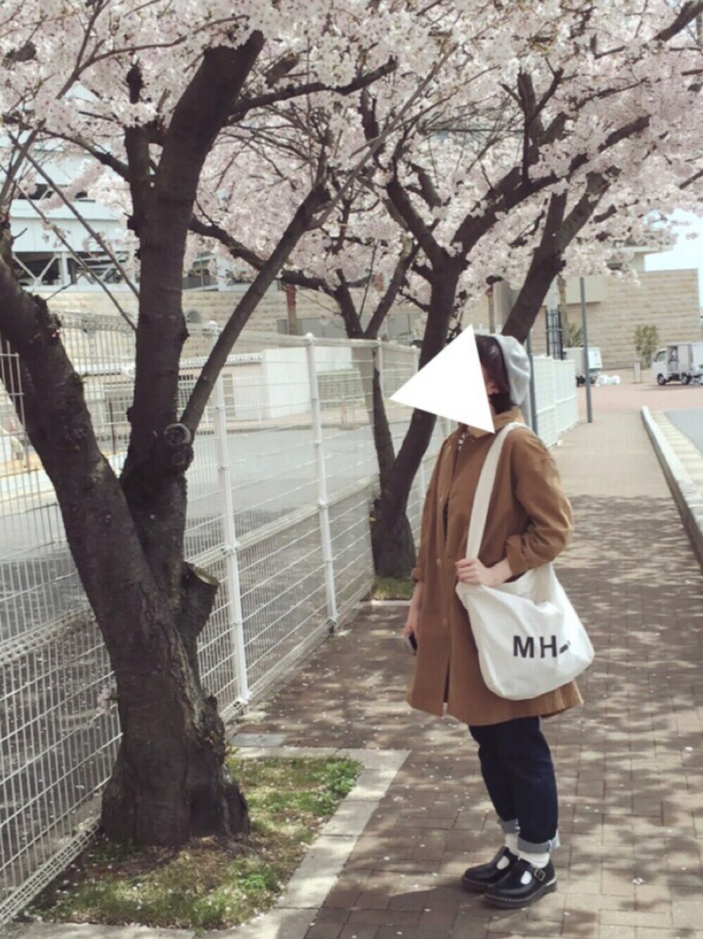 ベージュ系のステンカラーコート、ブルー系のデニムパンツ、ブラック系のその他シューズを着用したレディースの春コーディネートの1枚目の写真