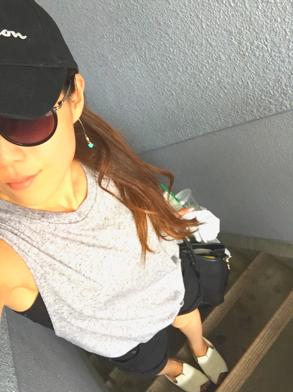 ブラック系のキャップを着用したレディースの夏コーディネートの1枚目の写真