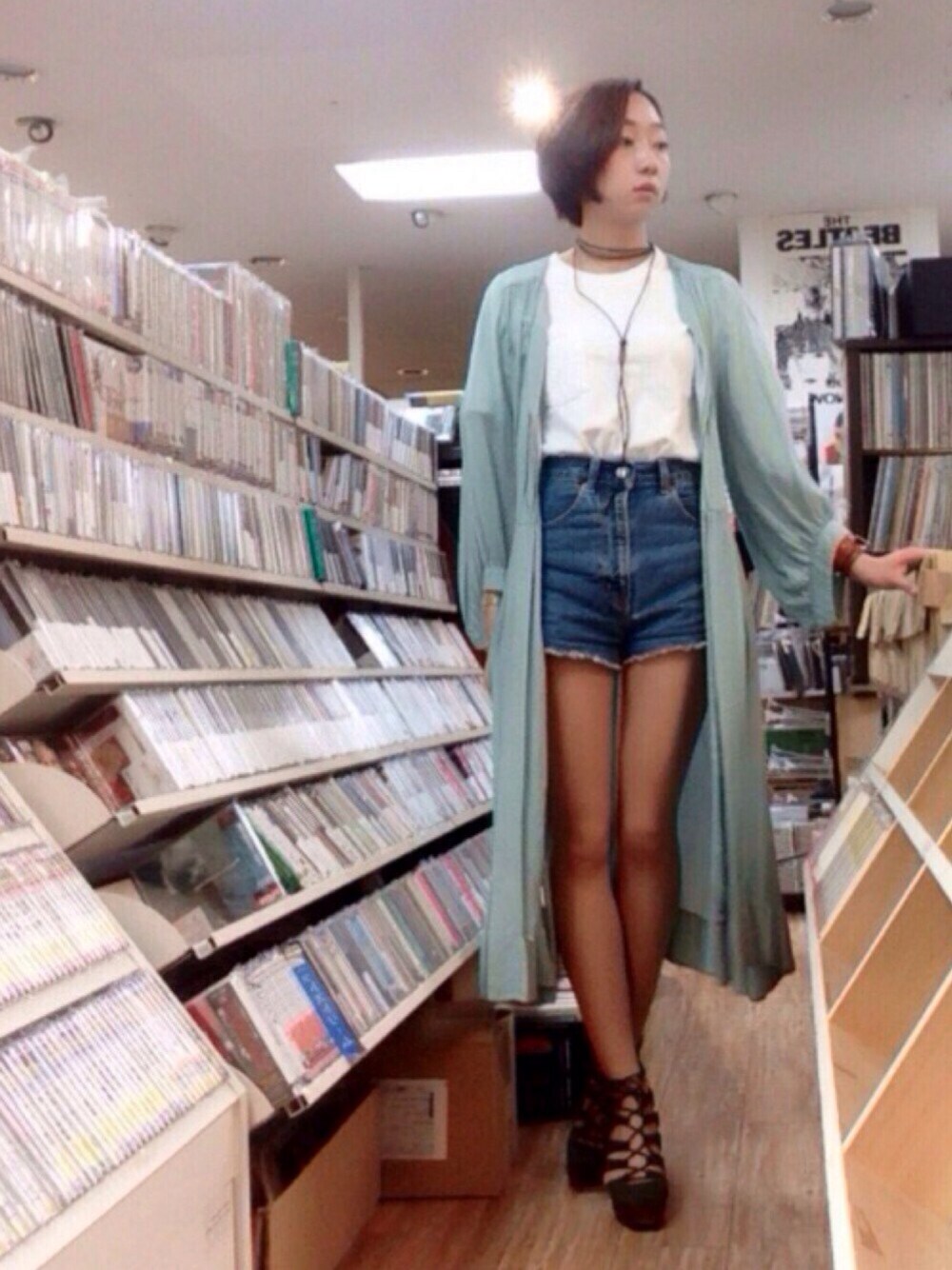 ブルー系のデニムパンツ、グリーン系のサンダル、ゴールド系のアナログ腕時計を着用したレディースの春コーディネートの1枚目の写真