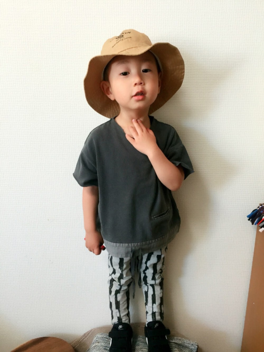 ブラック系のTシャツ/カットソー、ブラック系のスニーカー、ベージュ系のハットを着用したキッズの夏コーディネートの1枚目の写真