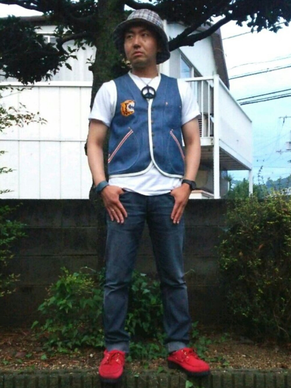 ブルー系のデニムパンツ、レッド系のモカシン/デッキシューズ、ブルー系のベストを着用したメンズの夏コーディネートの1枚目の写真