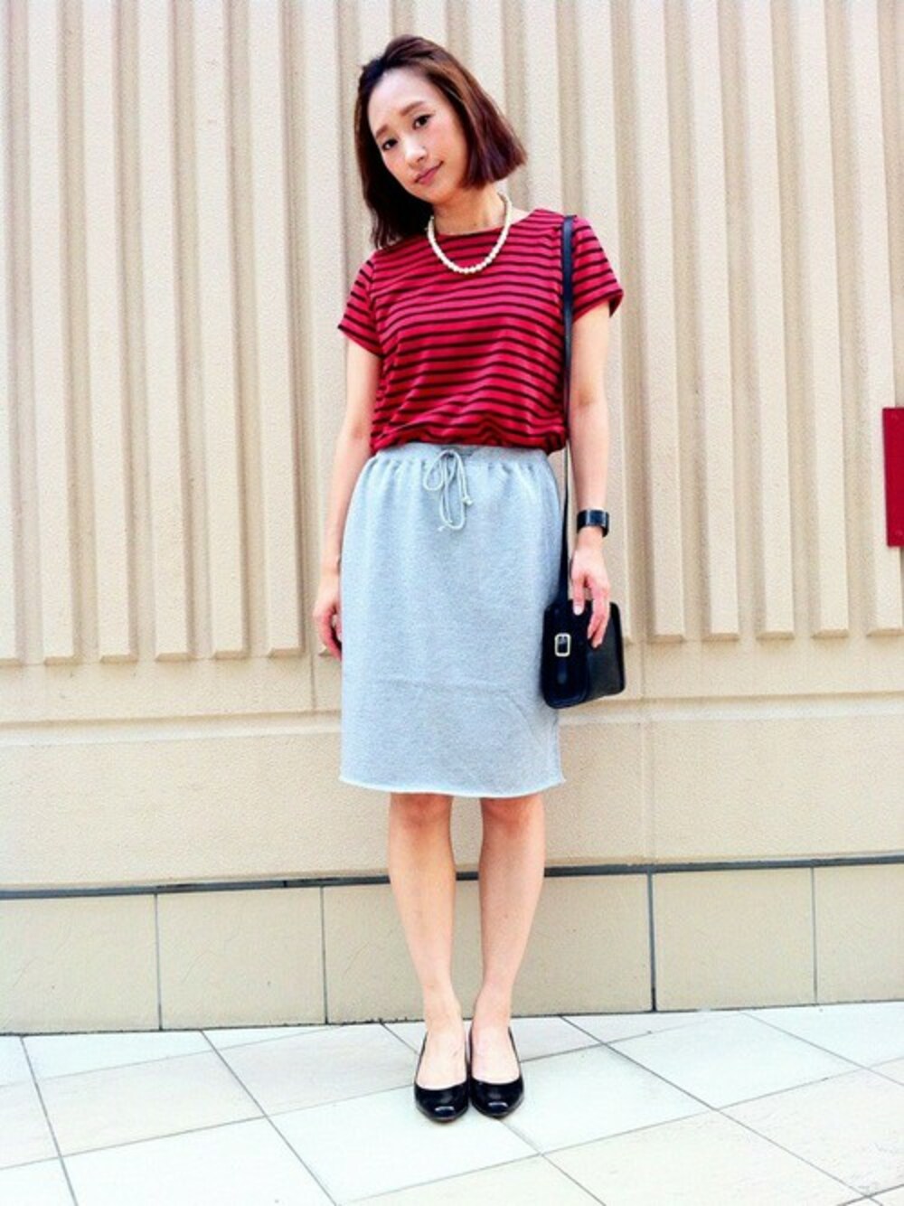グレー系のスカート、ブラック系のパンプスを着用したレディースの夏コーディネートの1枚目の写真