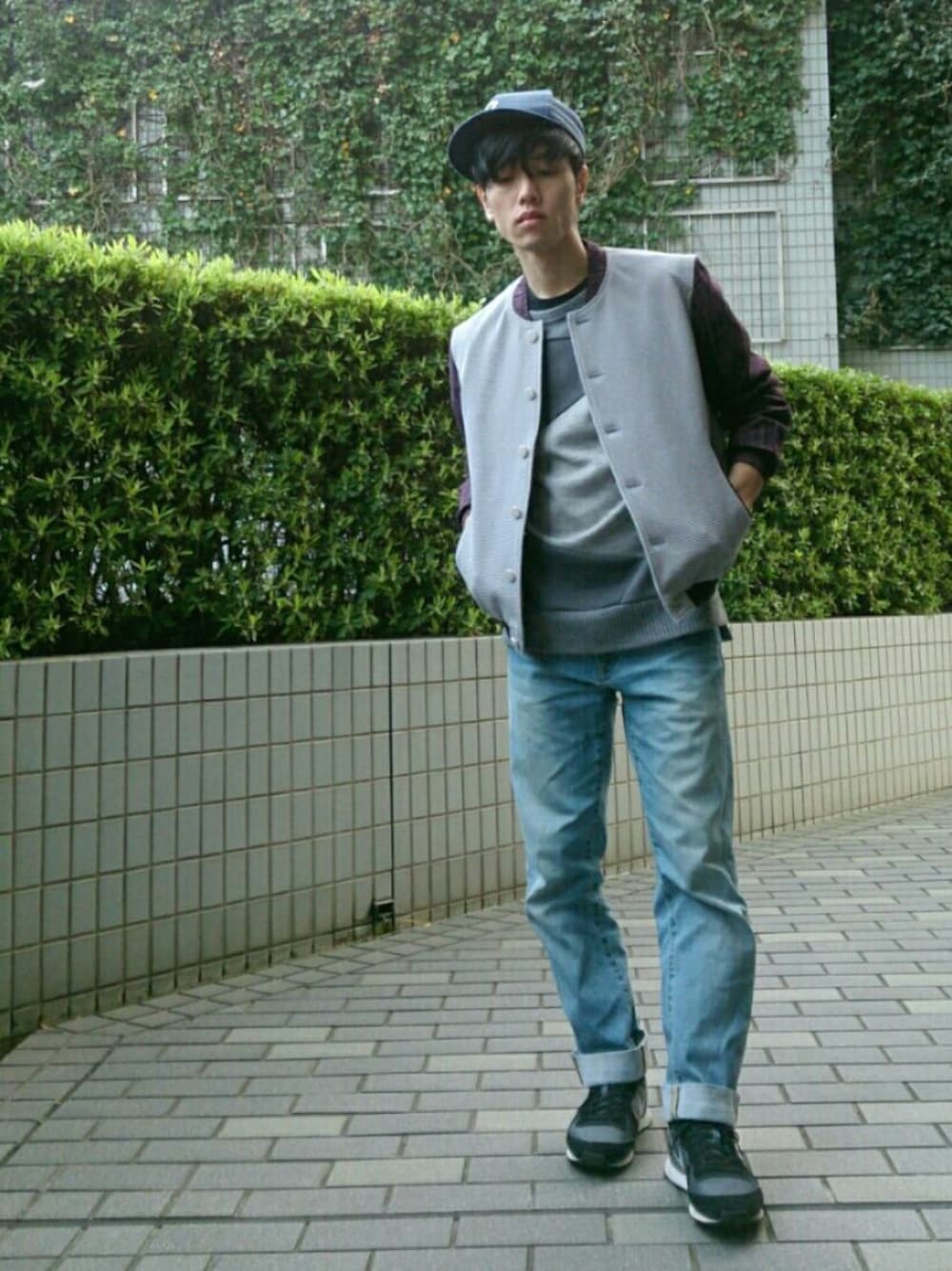 グレー系のブルゾン、ブラック系のスニーカー、ブルー系のデニムパンツを着用したメンズの春コーディネートの1枚目の写真