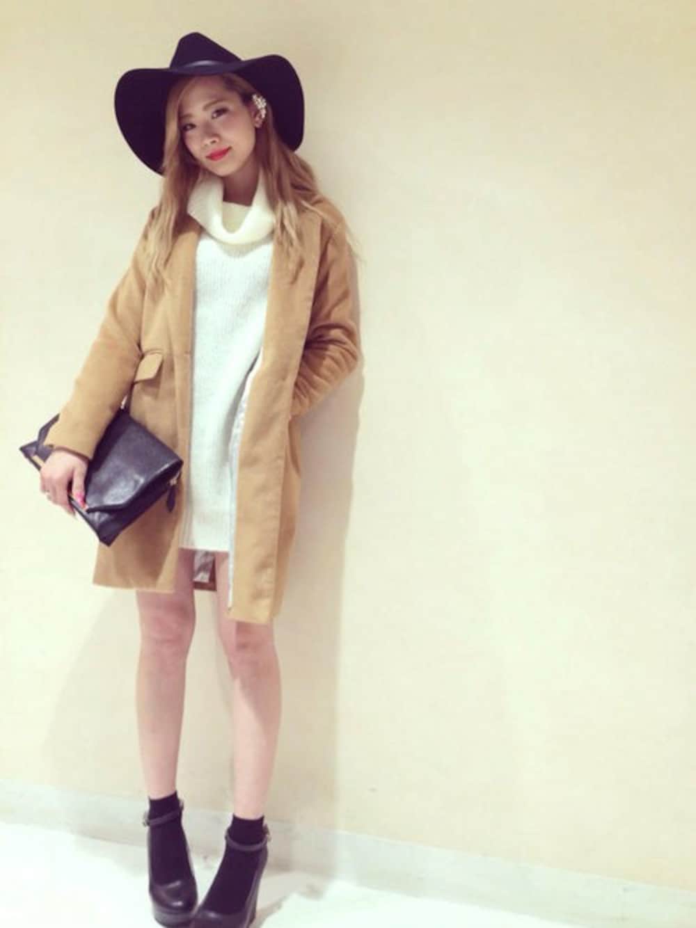 ホワイト系のチュニック、ブラウン系のチェスターコート、ブラック系のクラッチバッグを着用したレディースの冬コーディネートの1枚目の写真