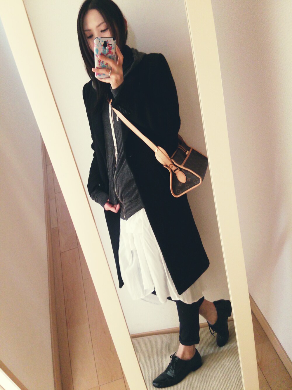 ブラウン系のショルダーバッグ、ブラック系のチェスターコート、ブラック系のドレスシューズを着用したレディースの冬コーディネートの1枚目の写真