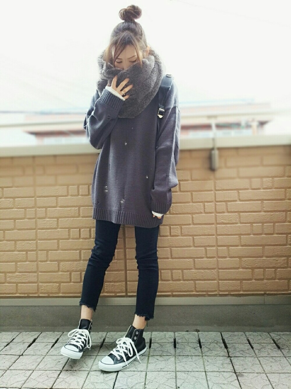 グレー系のニット/セーター、ホワイト系のTシャツ/カットソー、ブラック系のデニムパンツを着用したレディースの冬コーディネートの1枚目の写真