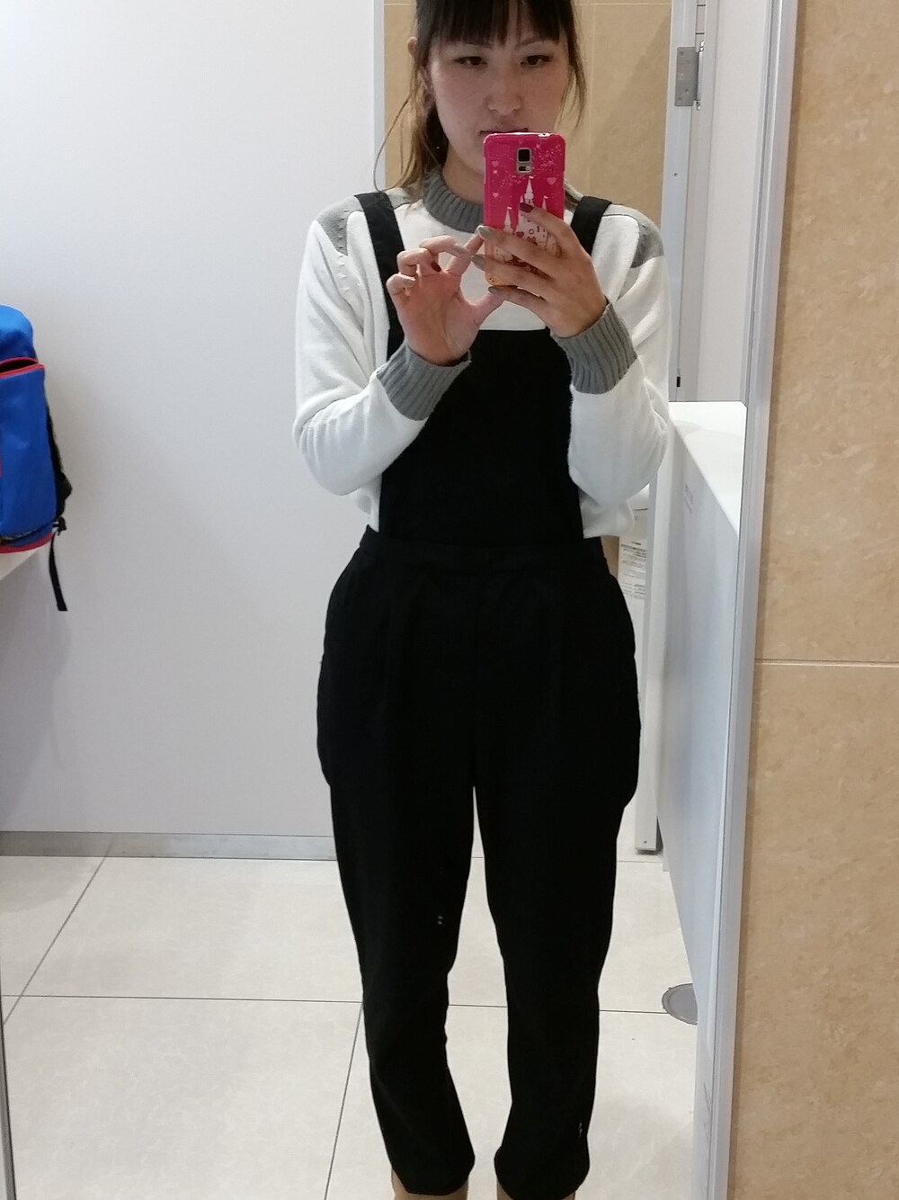 ブラック系のサロペット/オーバーオール、ブラウン系のブーツ、ホワイト系のニット/セーターを着用したレディースの秋コーディネートの1枚目の写真