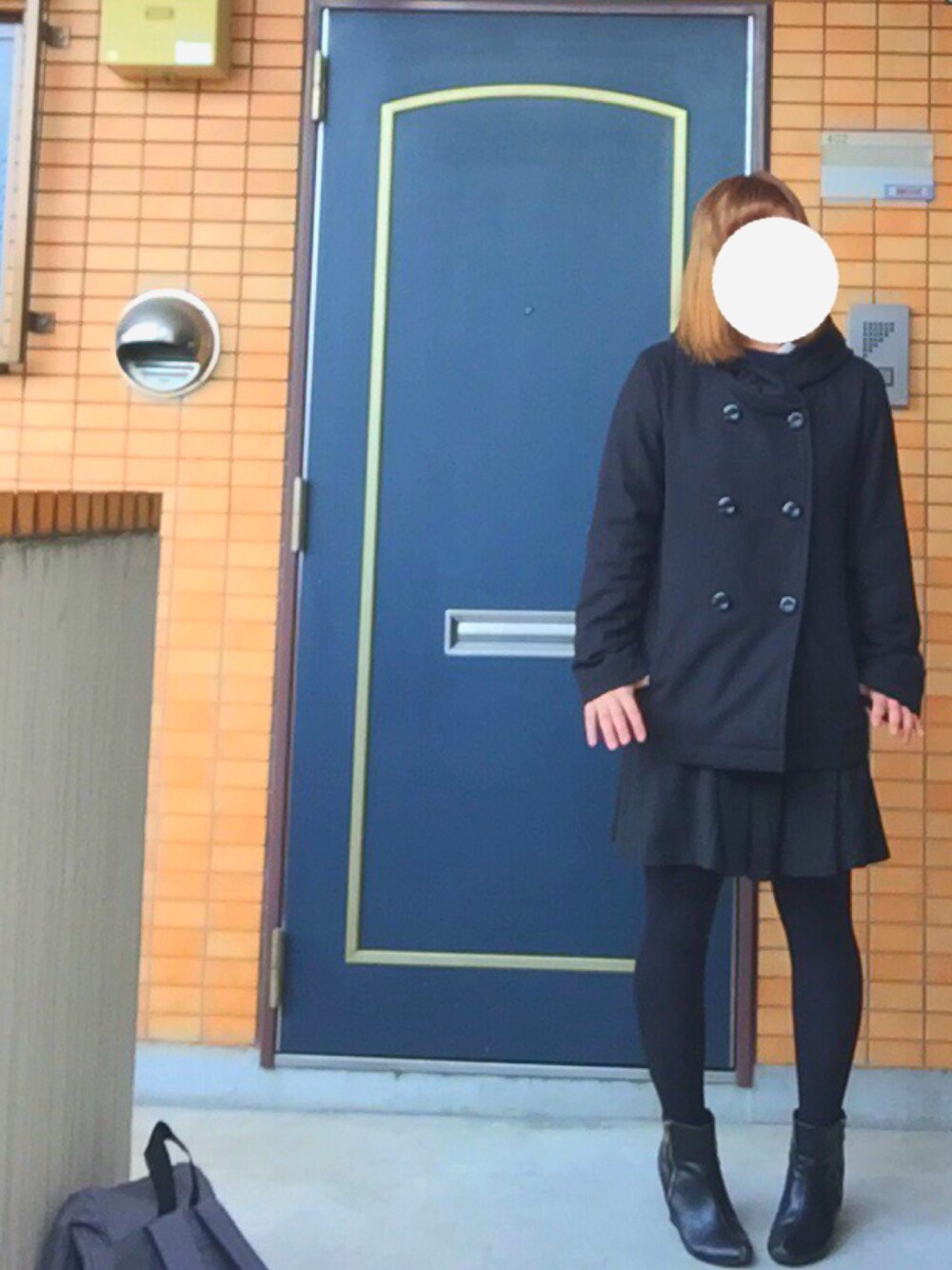 ブラック系のダウンジャケット/コート、ブラック系のスカート、ブルー系のニット/セーターを着用したレディースの春コーディネートの1枚目の写真