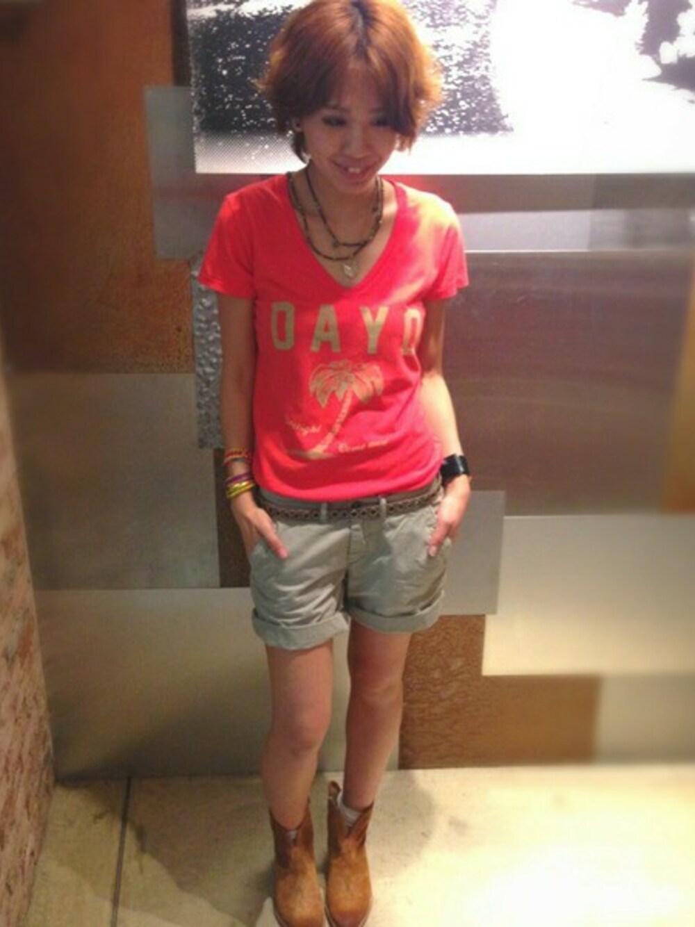 レッド系のTシャツ/カットソー、グレー系のカーゴパンツ、ブラウン系のブーツを着用したレディースの春コーディネートの1枚目の写真