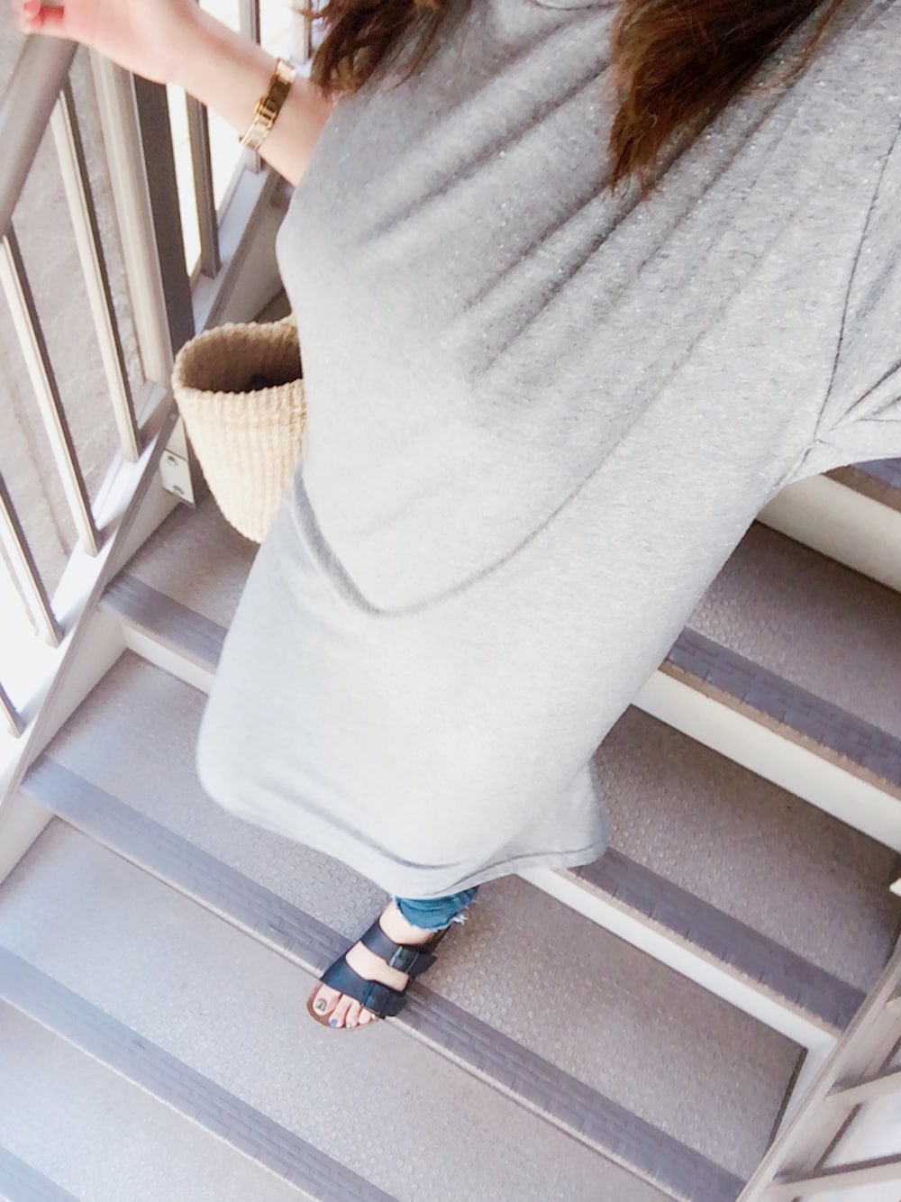 グレー系のワンピース、ブラック系のサンダル、ブルー系のデニムパンツを着用したレディースの夏コーディネートの1枚目の写真