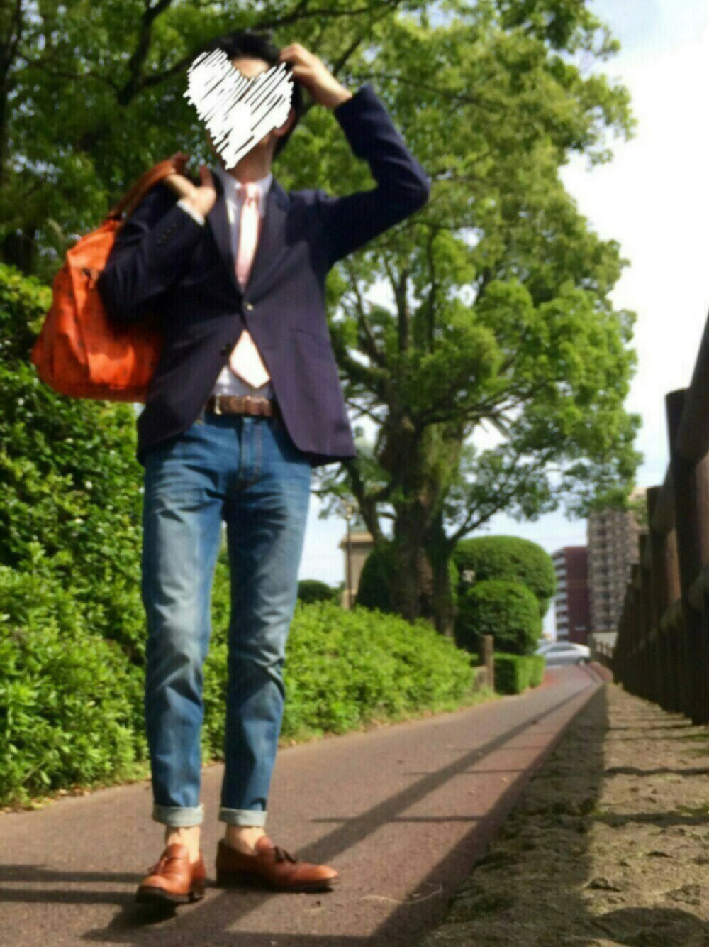 ブラウン系のドレスシューズ、ブルー系のデニムパンツ、オレンジ系のボストンバッグを着用したメンズの春コーディネートの1枚目の写真