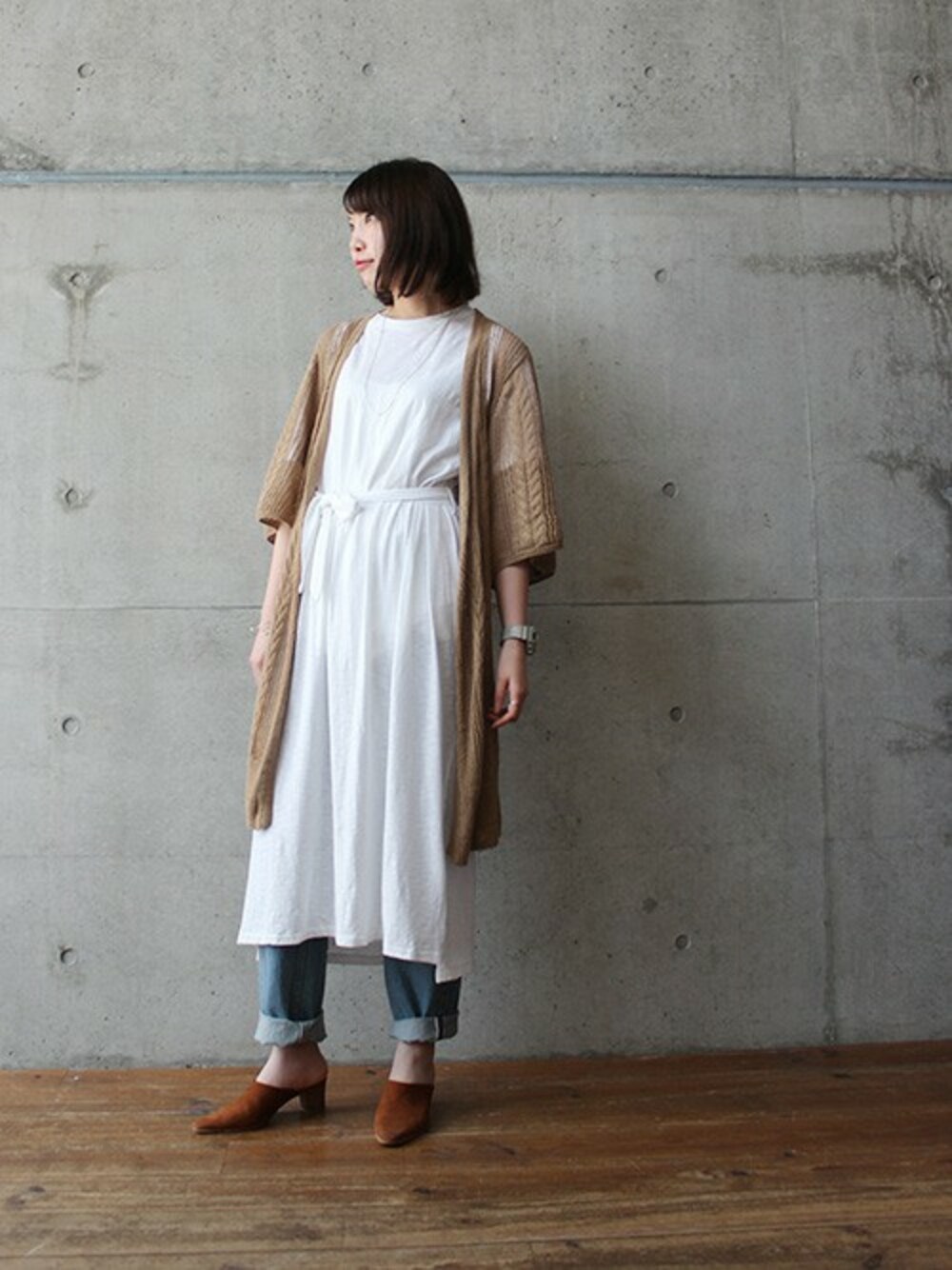 ベージュ系のカーディガン/ボレロ、ホワイト系のワンピース、ブルー系のデニムパンツを着用したレディースの春コーディネートの1枚目の写真