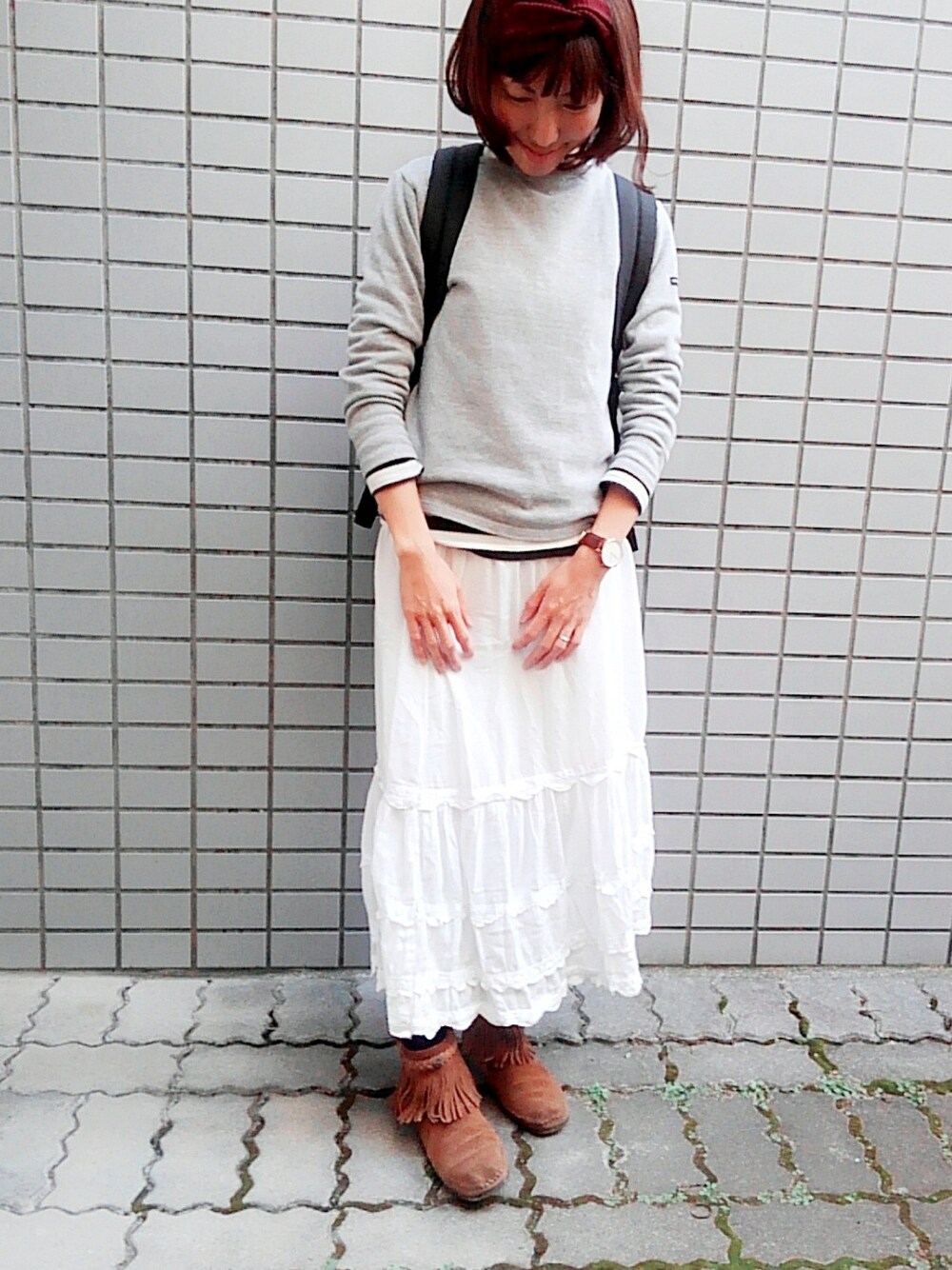 グレー系のトップス、ブラウン系のシューズ、ホワイト系のスカートを着用したレディースの秋コーディネートの1枚目の写真