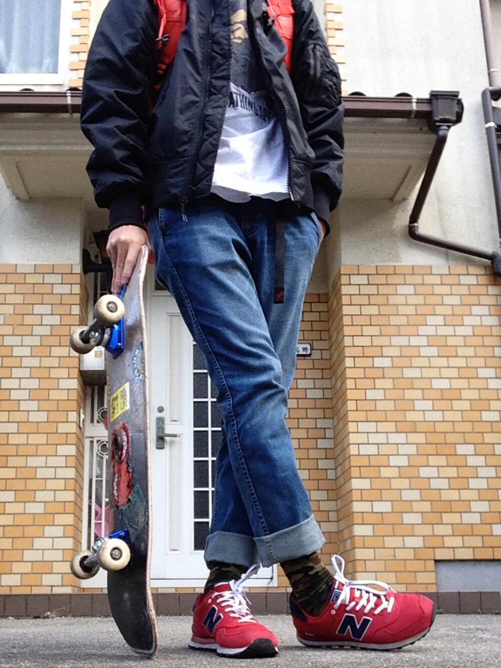 ブラック系のナイロンジャケット、ホワイト系のTシャツ/カットソー、オレンジ系のバックパック/リュックを着用したメンズの冬コーディネートの1枚目の写真
