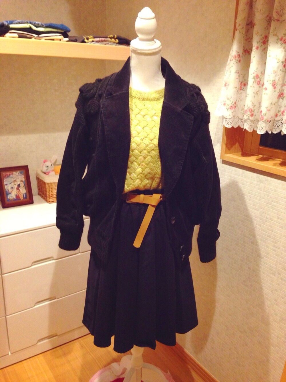 グリーン系のニット/セーター、ブラック系のスカート、ブラック系のブルゾンを着用したレディースの秋コーディネートの1枚目の写真