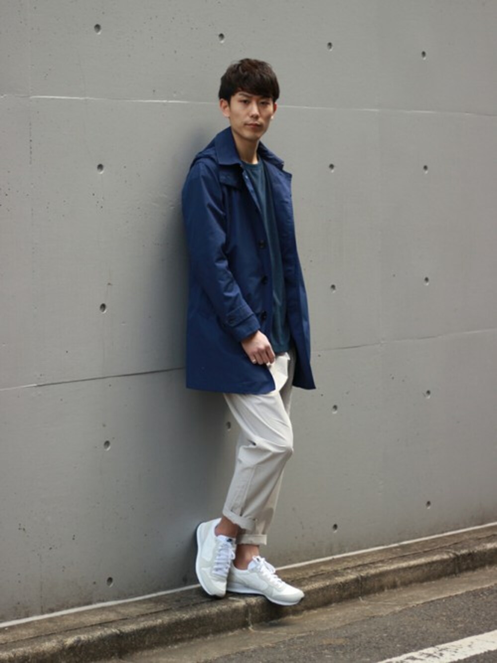 ブルー系のステンカラーコート、グレー系のその他パンツ、ホワイト系のスニーカーを着用したメンズの冬コーディネートの1枚目の写真