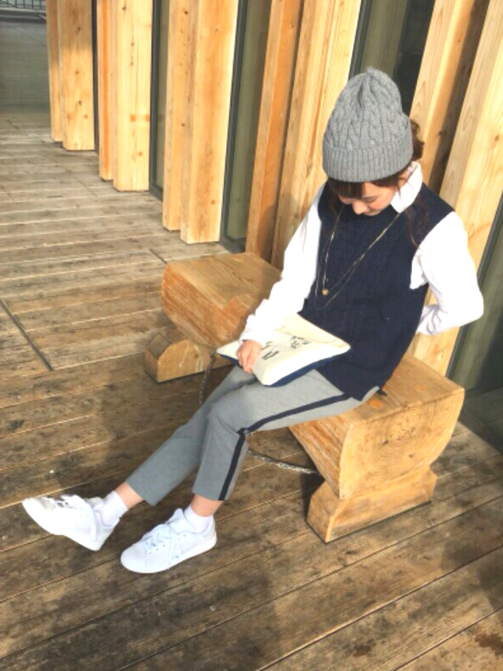 グレー系のパンツ、ブルー系のトップス、ホワイト系のスニーカーを着用したレディースの冬コーディネートの1枚目の写真