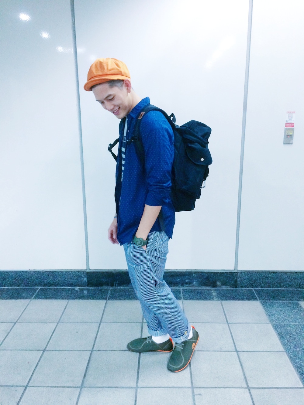 グリーン系のスニーカー、ブラック系のバックパック/リュック、オレンジ系のキャップを着用したメンズの夏コーディネートの1枚目の写真