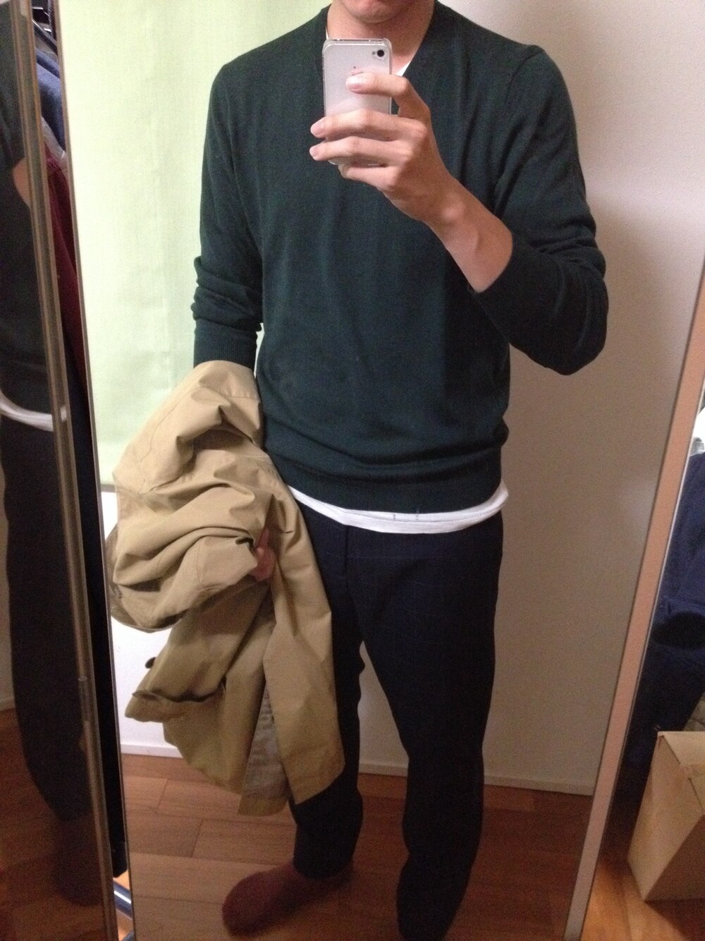 グリーン系のニット/セーター、ベージュ系のステンカラーコート、ブルー系のスラックスを着用したメンズの秋コーディネートの1枚目の写真