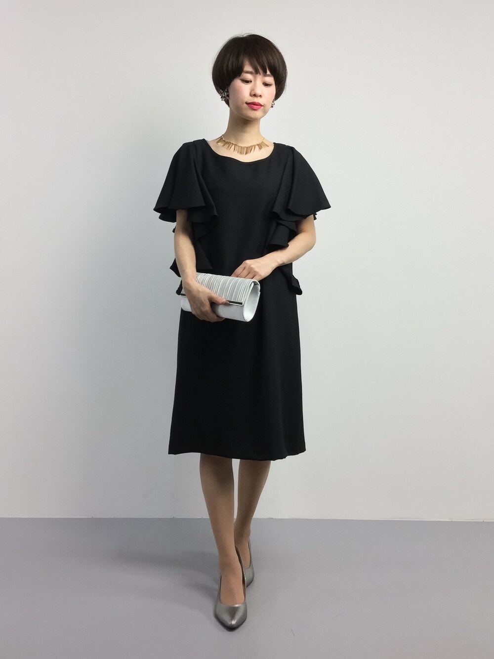 ブラック系のワンピース、グレー系のクラッチバッグを着用したレディースの夏コーディネートの1枚目の写真