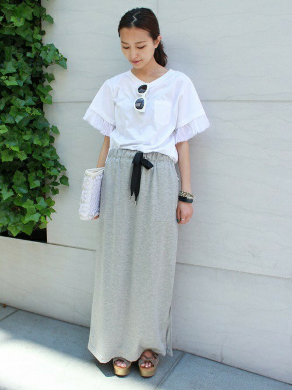 グレー系のスカート、ホワイト系のクラッチバッグ、ホワイト系のTシャツ/カットソーを着用したレディースの春コーディネートの1枚目の写真