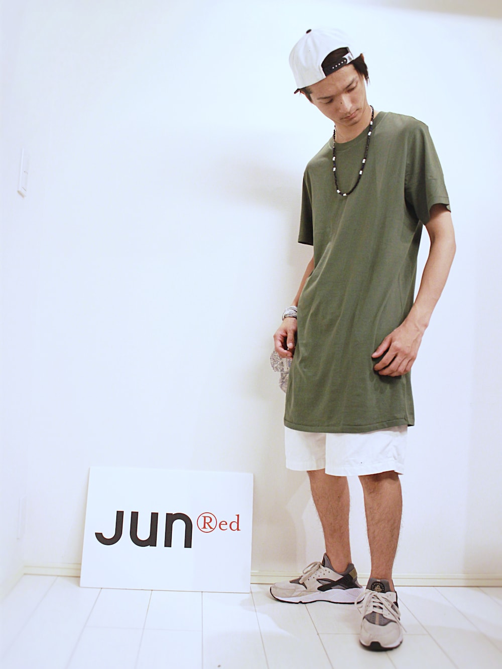 グリーン系のトップス、ホワイト系のパンツ、ホワイト系のスニーカーを着用したメンズの夏コーディネートの1枚目の写真