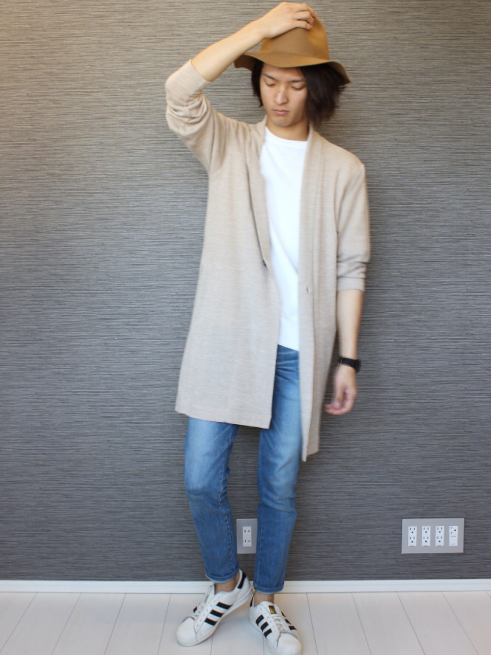 ベージュ系のカーディガン/ボレロ、ホワイト系のトップス、ブルー系のデニムパンツを着用したメンズの冬コーディネートの1枚目の写真