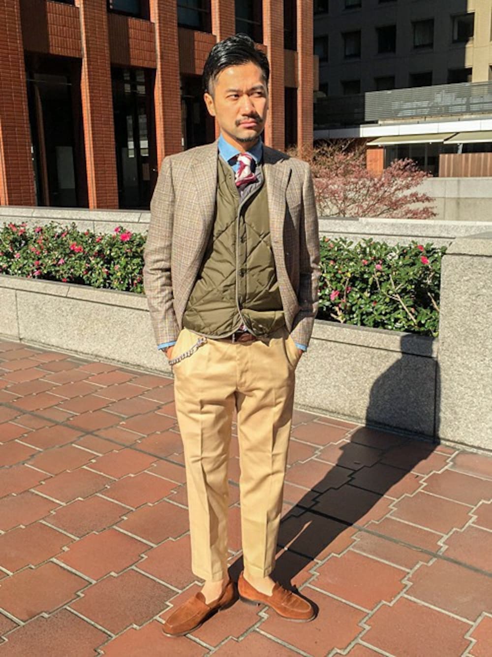 ブラウン系のテーラードジャケット、グリーン系のダウンベスト、ベージュ系のその他パンツを着用したメンズの冬コーディネートの1枚目の写真