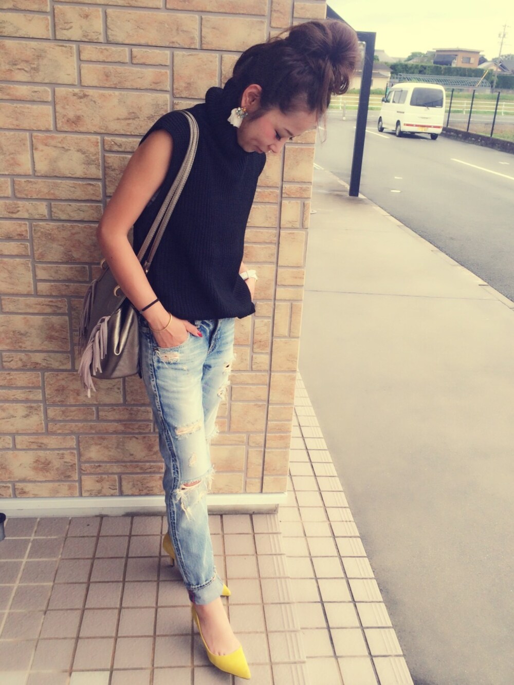 ブラック系のニット/セーター、ゴールド系のショルダーバッグ、ブルー系のデニムパンツを着用したレディースの秋コーディネートの1枚目の写真