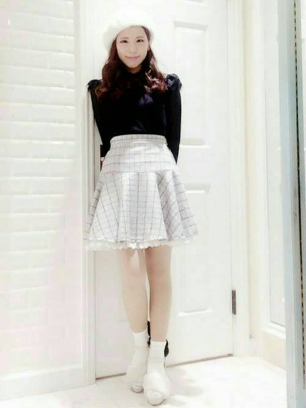 ホワイト系のスカート、ブラック系のニット/セーター、ホワイト系のハンチング/ベレー帽を着用したレディースの秋コーディネートの1枚目の写真