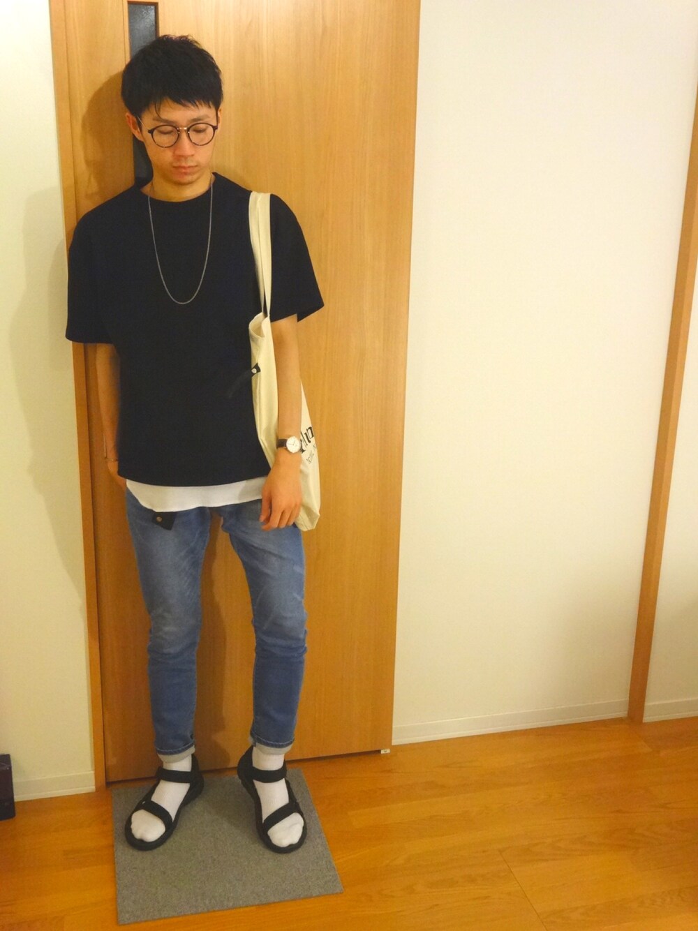 ブラック系のTシャツ/カットソー、ホワイト系のトートバッグ、ブルー系のデニムパンツを着用したメンズの夏コーディネートの1枚目の写真