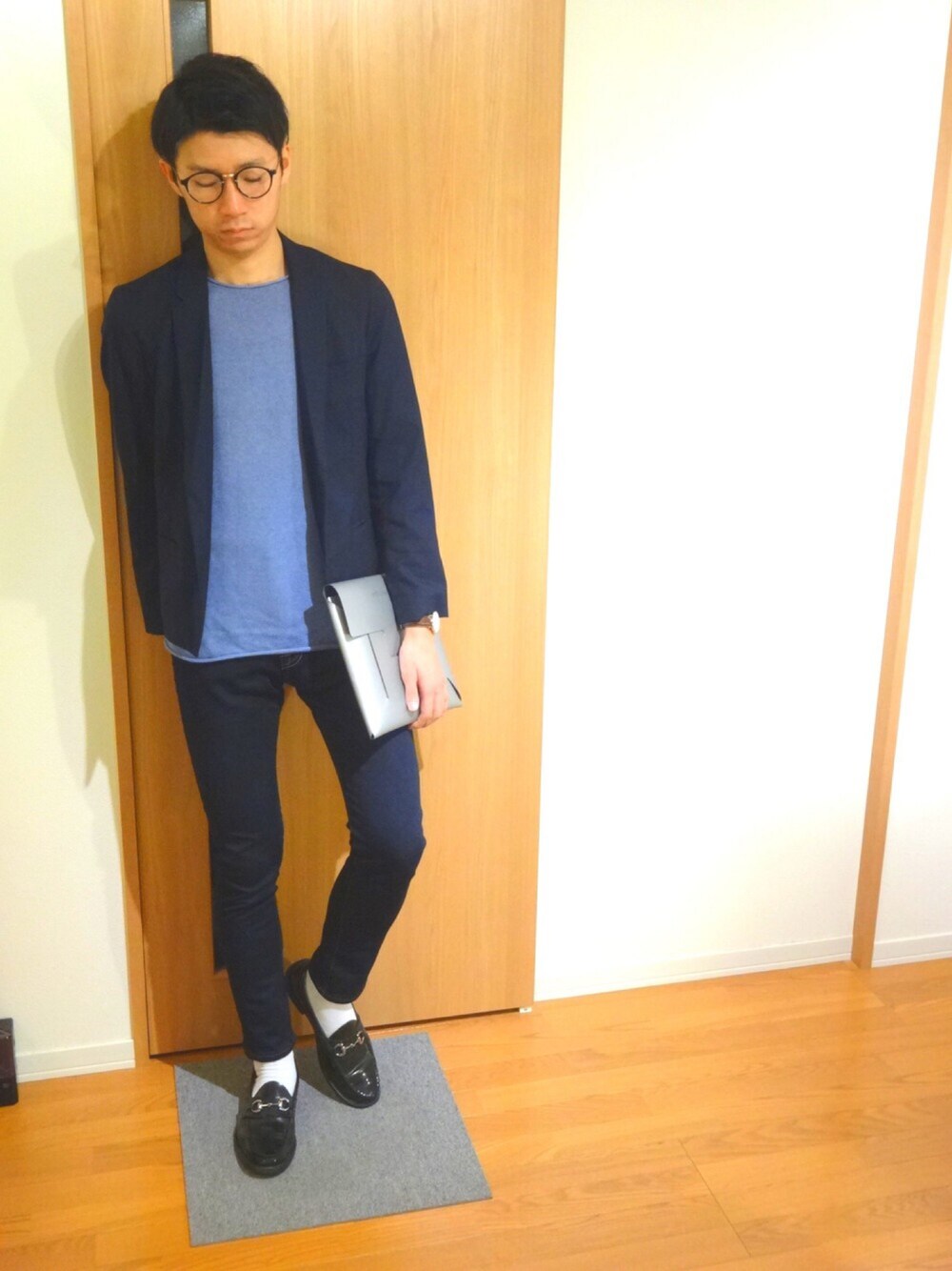 ブルー系のテーラードジャケット、ブルー系のニット/セーター、シルバー系のクラッチバッグを着用したメンズの秋コーディネートの1枚目の写真