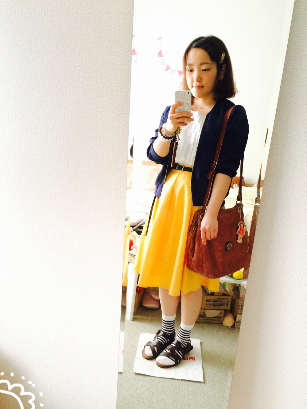 イエロー系のスカート、ホワイト系のシャツ/ブラウス、ブラウン系のサンダルを着用したレディースの春コーディネートの1枚目の写真