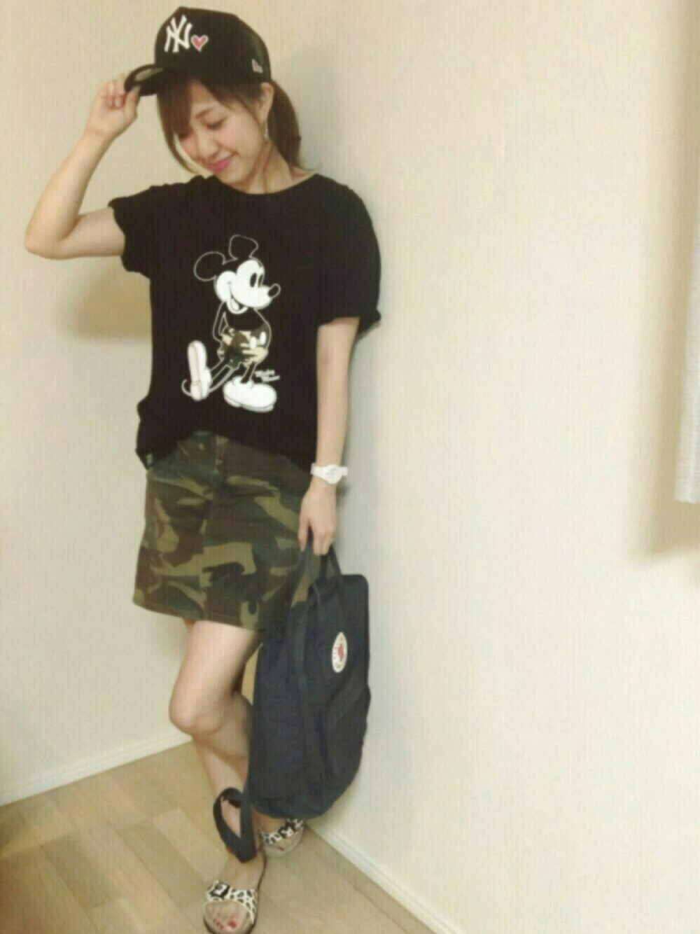 グリーン系のスカート、ブラック系のバックパック/リュック、ホワイト系のサンダルを着用したレディースの夏コーディネートの1枚目の写真