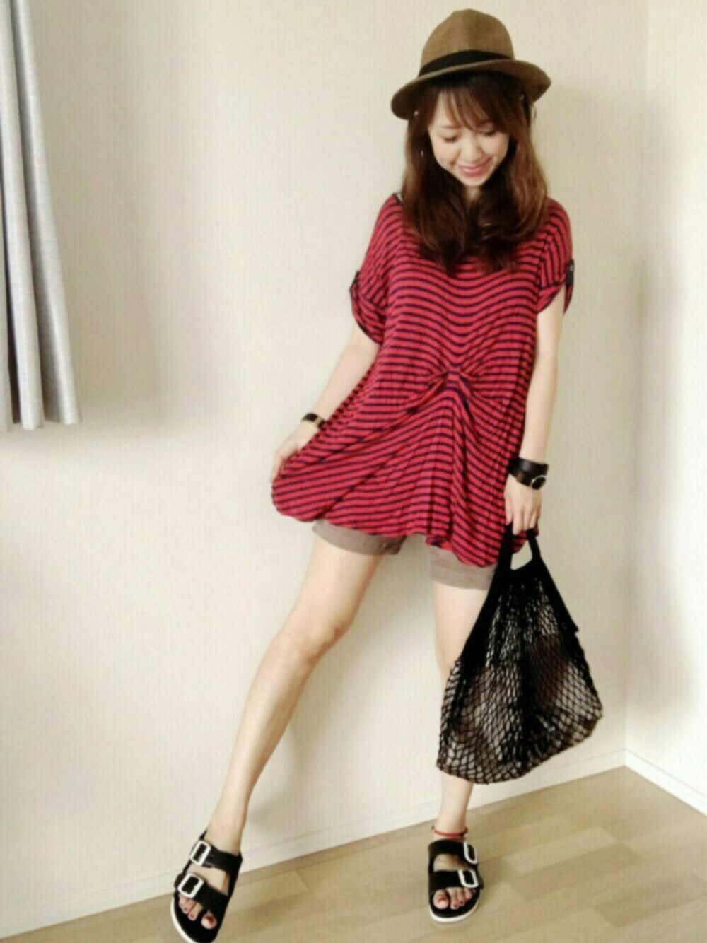 グリーン系のパンツ、ブラック系のエコバッグ/サブバッグ、レッド系のTシャツ/カットソーを着用したレディースの夏コーディネートの1枚目の写真