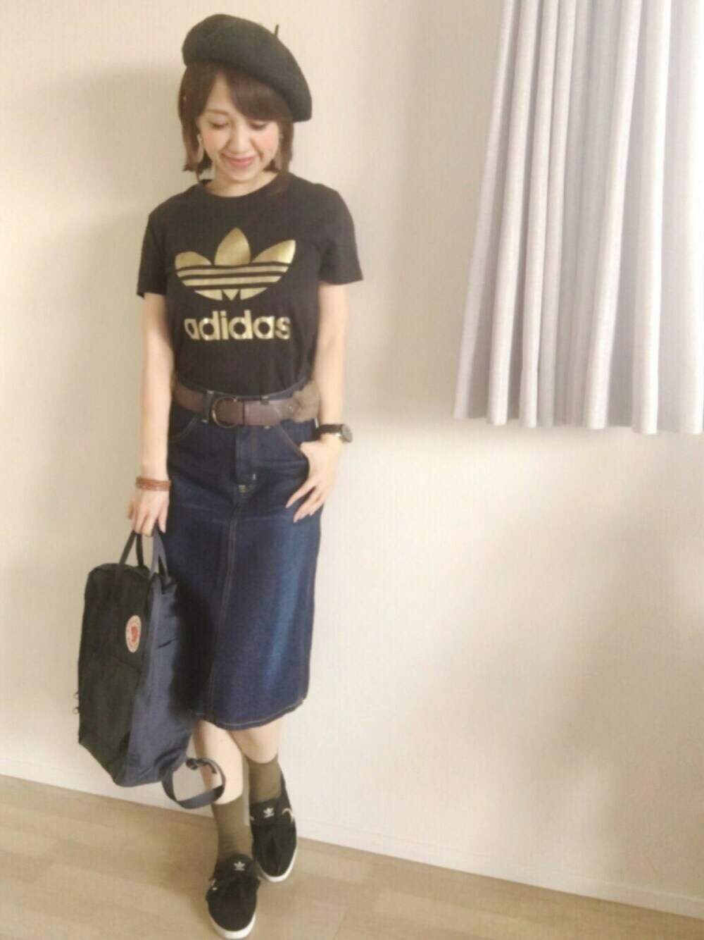 ブルー系のデニムスカート、ブラック系のTシャツ/カットソー、ブラック系のスニーカーを着用したレディースの秋コーディネートの1枚目の写真
