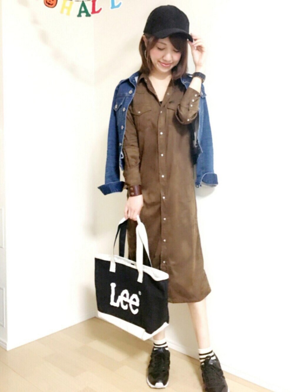 ブラウン系のシャツワンピース、ブラック系のトートバッグ、ブラック系のスニーカーを着用したレディースの秋コーディネートの1枚目の写真