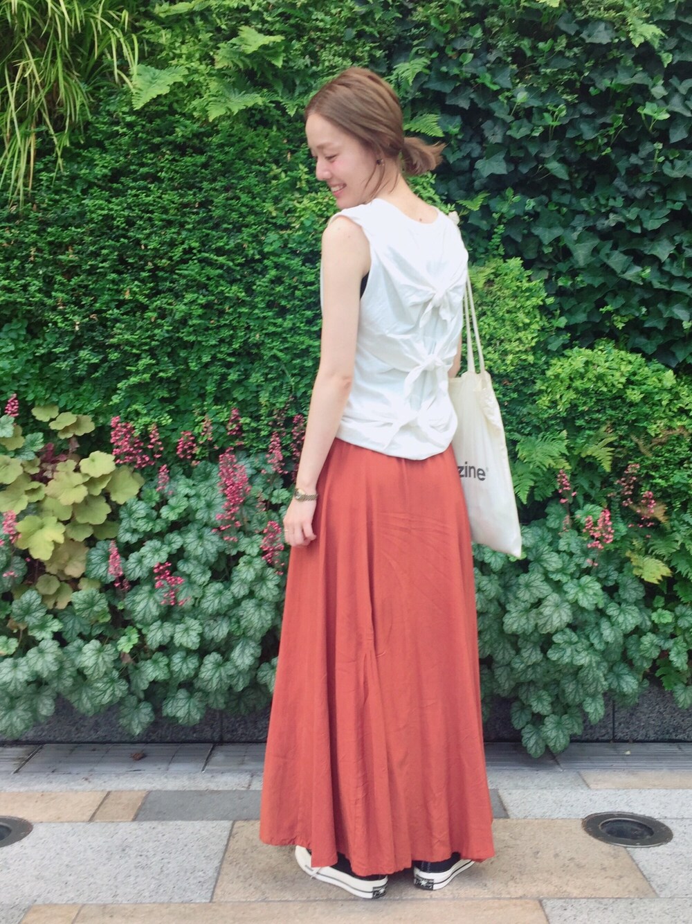 ホワイト系のTシャツ/カットソー、オレンジ系のスカート、ブラック系のスニーカーを着用したレディースの夏コーディネートの1枚目の写真