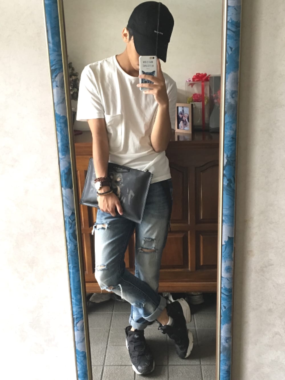 ブラック系のスニーカー、ブルー系のデニムパンツ、ブラック系のクラッチバッグを着用したメンズの夏コーディネートの1枚目の写真