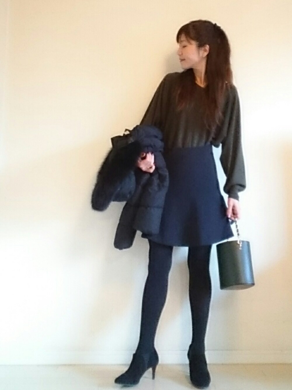 ブルー系のスカート、ブラック系のブーツ、グリーン系のハンドバッグを着用したレディースの冬コーディネートの1枚目の写真