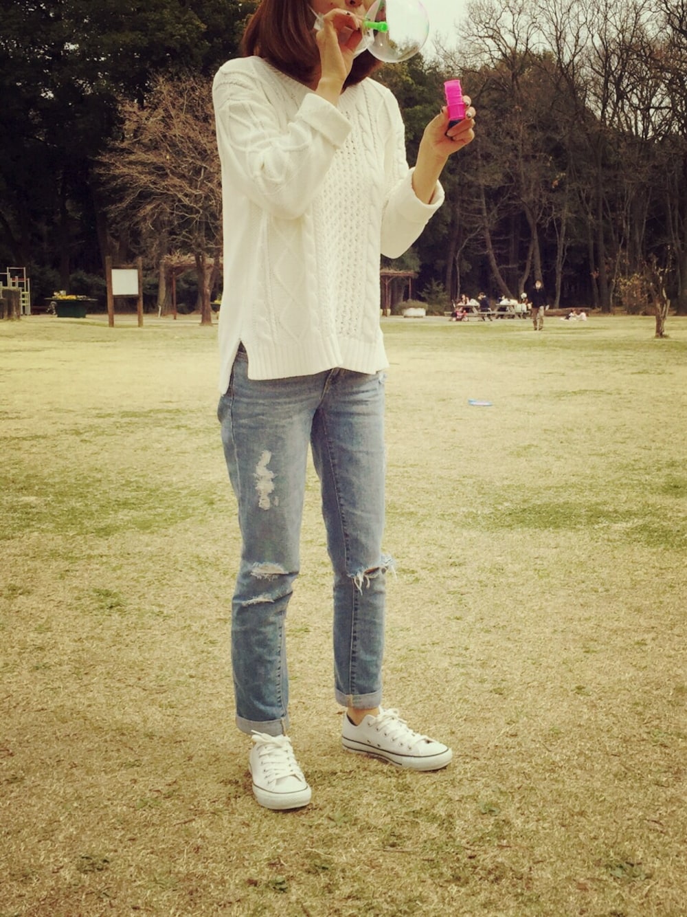 ホワイト系のニット/セーター、ブルー系のデニムパンツ、ホワイト系のスニーカーを着用したレディースの春コーディネートの1枚目の写真