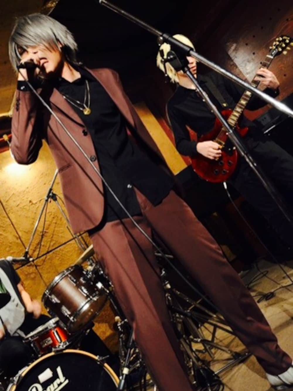 レッド系のテーラードジャケット、レッド系のスラックス、ホワイト系のブーツを着用したメンズの冬コーディネートの1枚目の写真