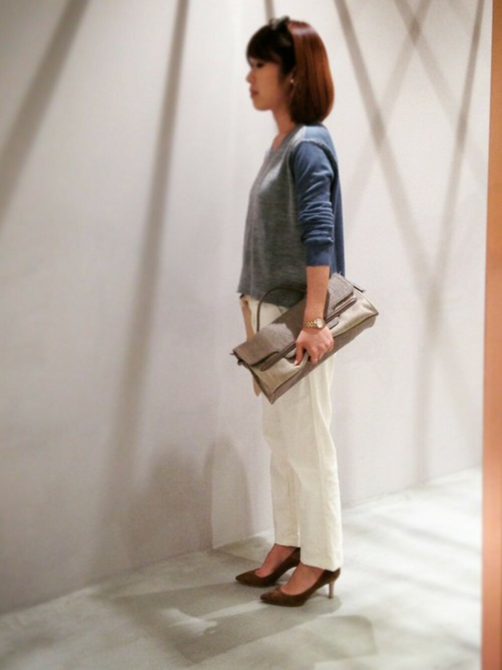 ブルー系のニット/セーター、ベージュ系のパンプス、グレー系のショルダーバッグを着用したレディースの春コーディネートの1枚目の写真