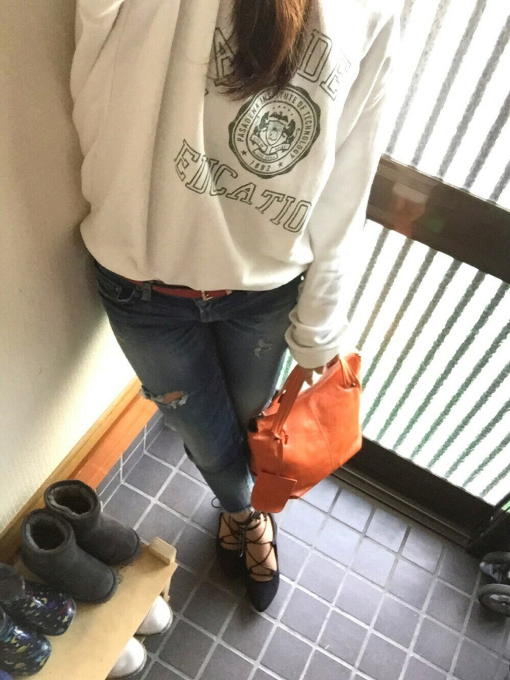 オレンジ系のトートバッグ、ホワイト系のスウェット、ブラック系のパンプスを着用したレディースの春コーディネートの1枚目の写真